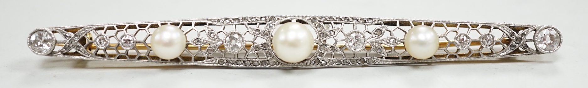 A Belle Epoque pierced yellow and white metal, cultured? pearl and diamond set bar brooch, 84mm, gross weight 10 grams, in fitted leather box.